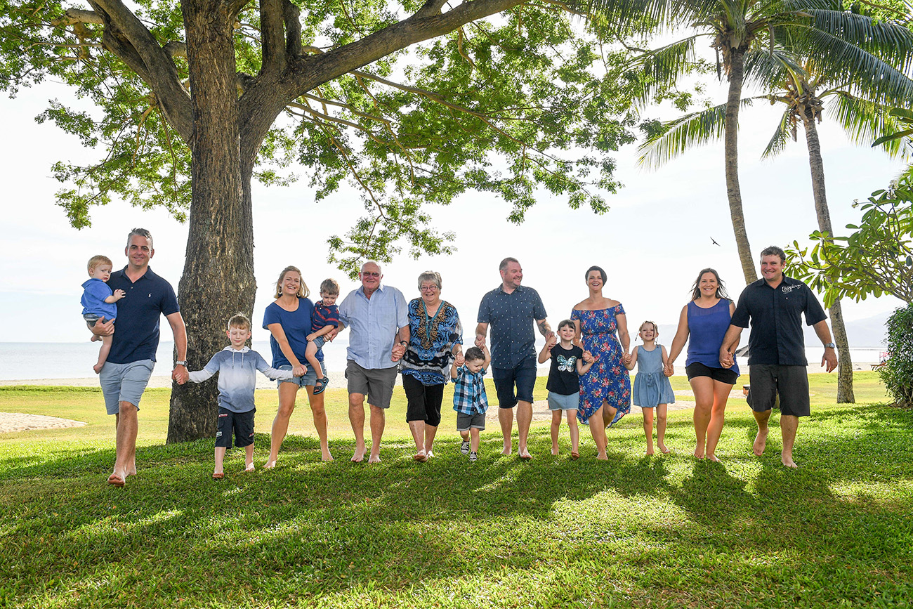 The extended family holds hands while on manicured Fiji grass