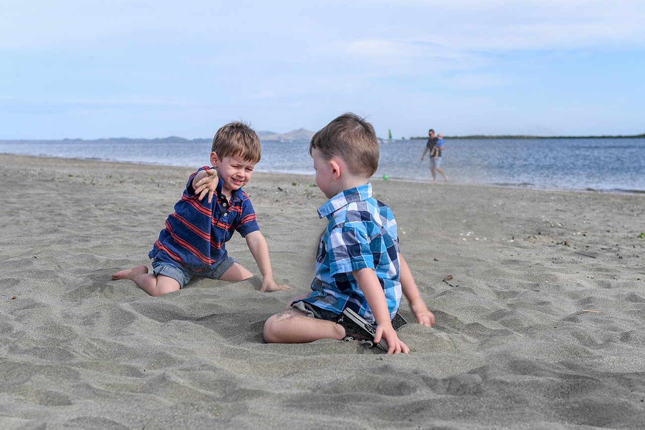 Two brothers playing with sand on the beach
