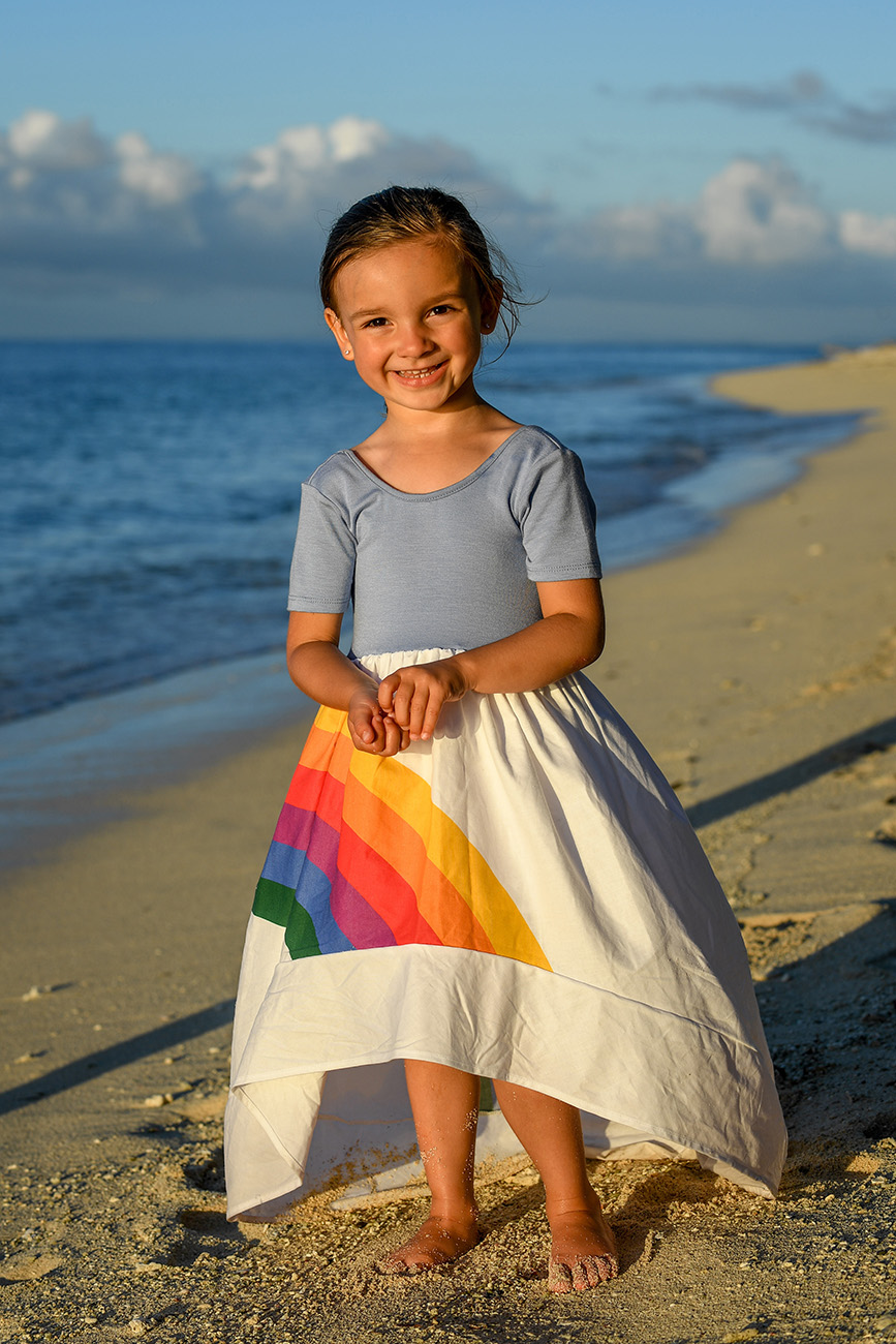 A full frame photo of a girl in a rainbow dress