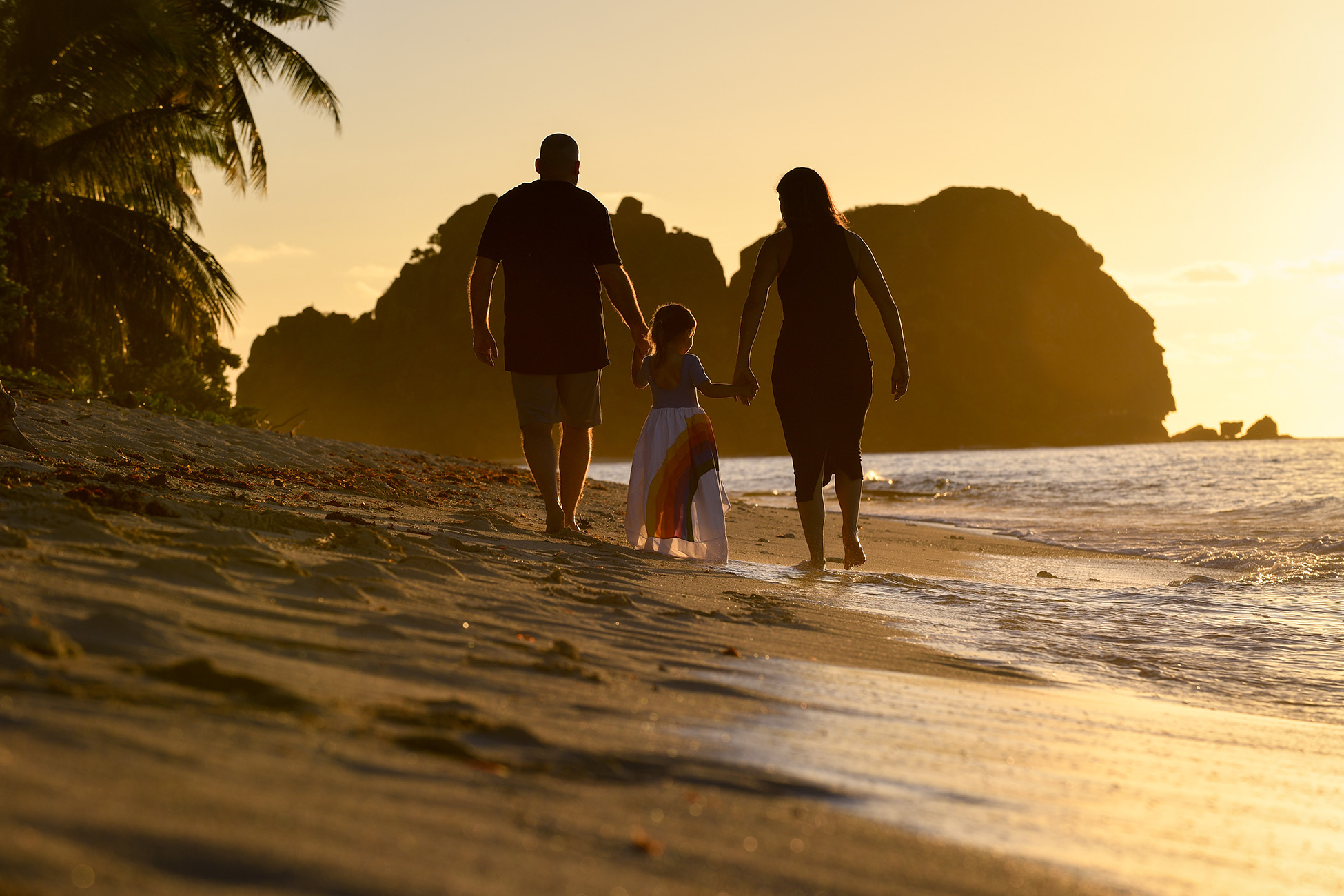 A golden haze glows on the family as they stroll on the beach at sunset