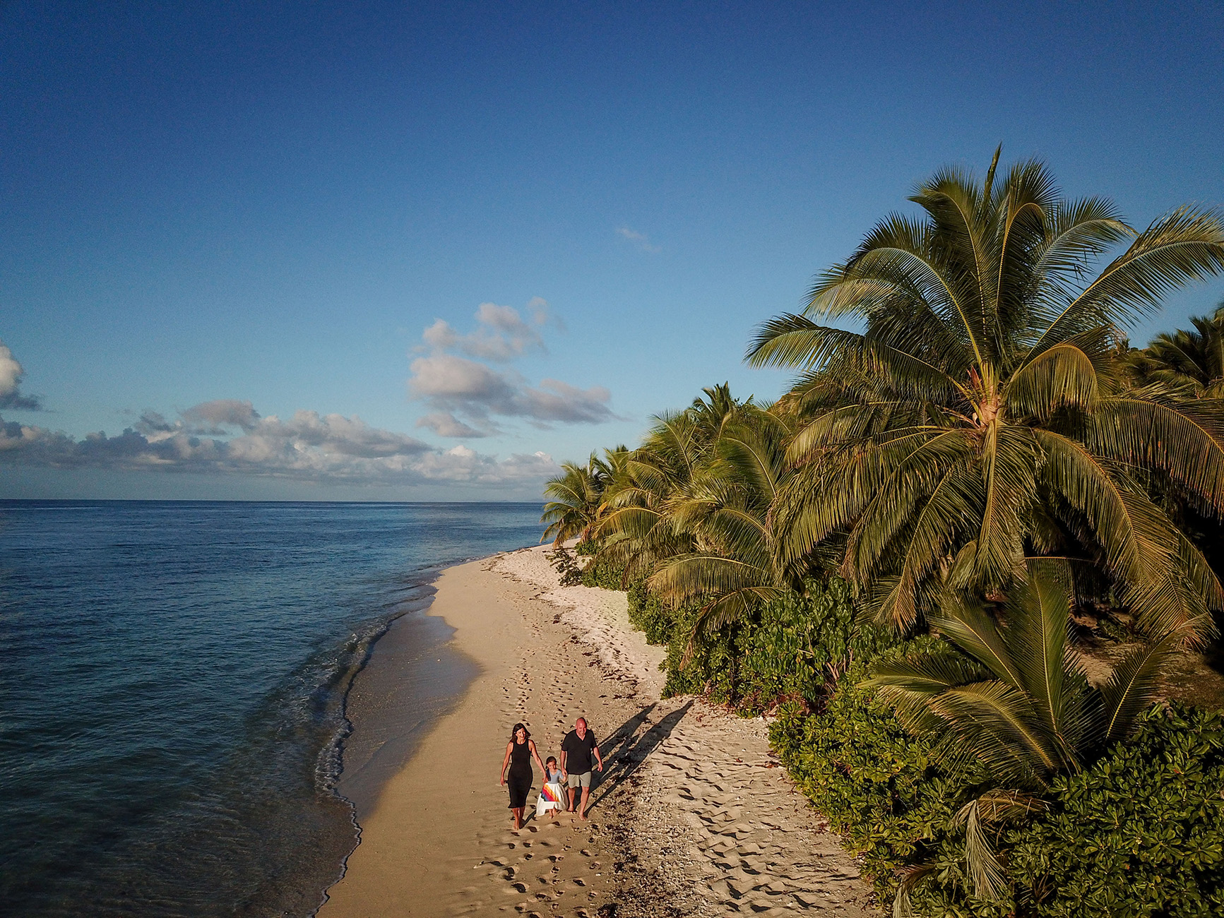 An aerial view of the family strolling on the beach of Vomo Island